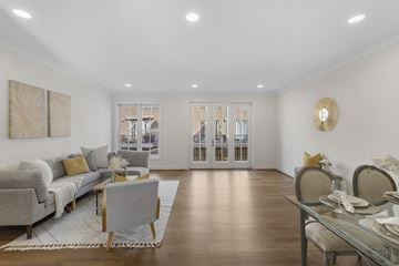 Baltimore apartment for rent - A modern living room with a grey sofa and a glass dining table.