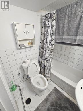 Brampton (Downtown Brampton) apartment for rent - A bathroom with a toilet, a shower curtain, and a cabinet above the toilet.