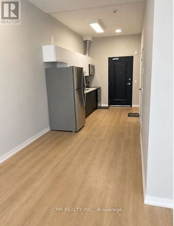 Peterborough (Town Ward 3) condo for rent - A kitchen area with a refrigerator and a door on the right.