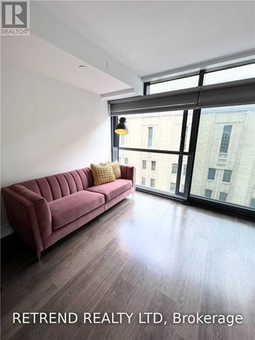 Toronto (Church-Yonge Corridor) condo for rent - A living room with a red couch and a window overlooking a city.