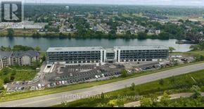 Welland (Broadway) condo for rent - A large building complex with a parking lot in front, situated in a suburban area.