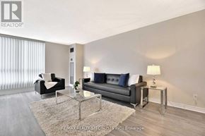 Toronto (Beechborough-Greenbrook) condo for rent - A living room with a black couch, a glass table, and a white lamp.
