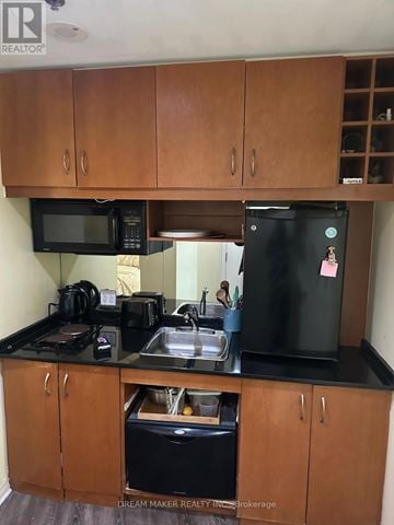 Toronto (Bay Street Corridor) condo for rent - A kitchen with black appliances and wooden cabinets.