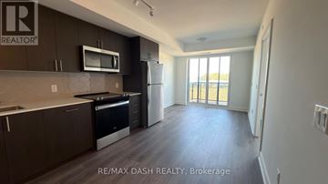 Oshawa (Windfields) condo for rent - A kitchen with dark brown cabinets and a microwave above the stove.