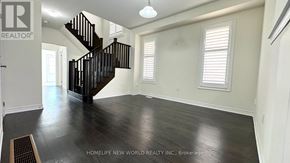 East Gwillimbury apartment for rent - A spacious room with a black staircase and wooden flooring.