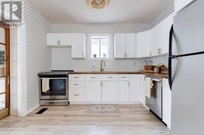 Hamilton (Eastmount) apartment for rent - A kitchen with white cabinets and a black and white tiled backsplash.