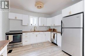 Hamilton (Eastmount) apartment for rent - A kitchen with white cabinets and a black stove top oven.