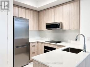Oakville (Ga Glen Abbey) condo for rent - A modern kitchen with a refrigerator, microwave, and stove top oven.