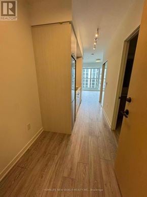 Toronto (Regent Park) condo for rent - A long hallway with wood flooring and white walls.