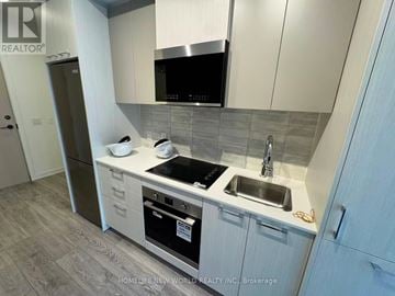 Toronto (Regent Park) condo for rent - A modern kitchen with a stainless steel dishwasher and a microwave above the stove.