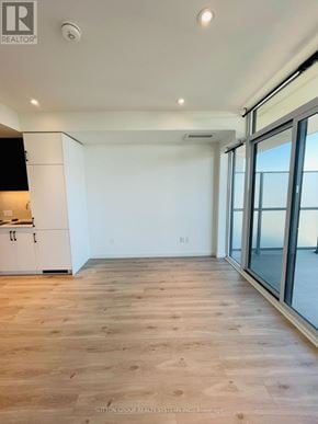Kitchener condo for rent - A spacious room with wooden flooring and a large window.