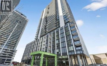 Vaughan (Vellore Village) condo for rent - A tall building with a green structure in front of it.