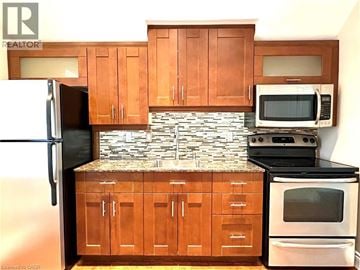Kitchener apartment for rent - A kitchen with wooden cabinets and a stone backsplash.