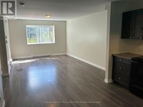 Huntsville (Chaffey) triplex for rent - A room with wooden flooring and a window with a view of trees.