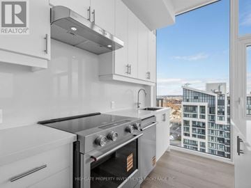 Vaughan (Vellore Village) condo for rent - A modern kitchen with a stove top oven and a window overlooking a cityscape.