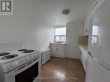 Hamilton (Durand) multi-family for rent - A white stove in a kitchen with a window and a countertop.