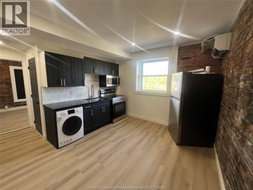 Windsor apartment for rent - A kitchen with black cabinets and a brick wall.