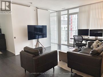 Toronto (Waterfront Communities) condo for rent - A living room with a brown couch and a flat screen TV mounted on the wall.