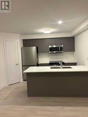 Guelph (Clairfields/Hanlon Business Park) townhouse for rent - A kitchen with a refrigerator, microwave, and a sink.