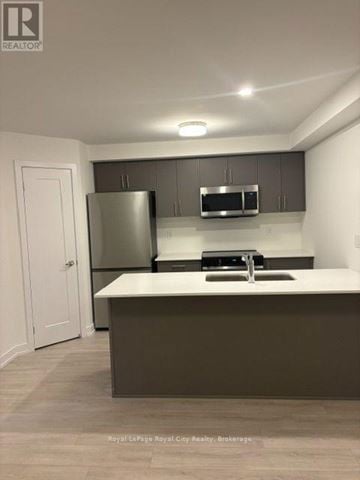 Guelph (Clairfields/Hanlon Business Park) townhouse for rent - A kitchen with a refrigerator, microwave, and a sink.