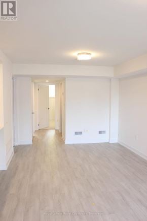 Guelph (Clairfields/Hanlon Business Park) townhouse for rent - A spacious room with wooden flooring and white walls.