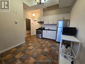 Toronto (Kensington-Chinatown) multi-family for rent - A kitchen with a tile floor and a refrigerator.