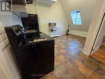 Toronto (Kensington-Chinatown) multi-family for rent - A kitchen with a black stove top oven and a tiled floor.