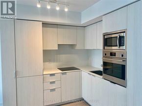 Toronto (Bay Street Corridor) condo for rent - A modern kitchen with white cabinets and stainless steel appliances.