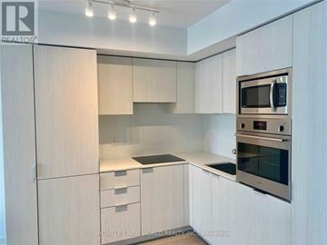Toronto (Bay Street Corridor) condo for rent - A modern kitchen with white cabinets and stainless steel appliances.