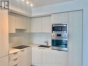 Toronto (Bay Street Corridor) condo for rent - A modern kitchen with a microwave and oven built into the cabinetry.