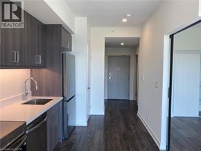 Welland condo for rent - A modern kitchen with dark wood floors and white countertops.