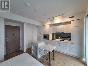 Toronto (Waterfront Communities) condo for rent - A modern kitchen with white cabinets and a dining table.