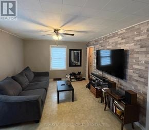 Welland (Lincoln/Crowland) apartment for rent - A living room with a grey couch, a black coffee table, a flat screen TV and a ceiling fan.