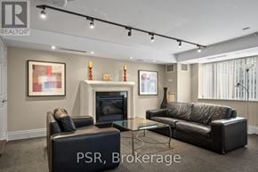 Toronto (Lawrence Park South) condo for rent - A living room with a black leather couch, a black ottoman, and a glass coffee table.