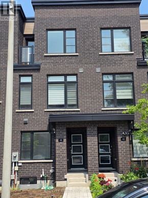 Toronto (Bendale) townhouse for rent - A brick building with a black front door and windows.
