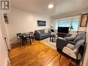 Hamilton (Inch Park) apartment for rent - A living room with a grey couch, a black chair, and a wooden floor.