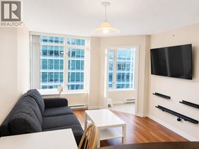 Vancouver apartment for rent - A living room with a black couch and a flat screen TV mounted on the wall.