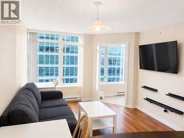 Vancouver apartment for rent - A living room with a black couch and a flat screen TV mounted on the wall.