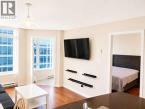 Vancouver apartment for rent - A bedroom with a bed, a couch, a table, and a television.