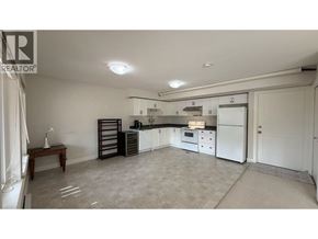 Coquitlam apartment for rent - A spacious kitchen with white appliances and a dining table.