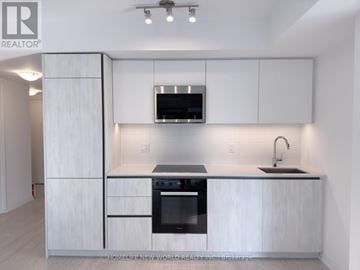Toronto (Waterfront Communities) condo for rent - A modern kitchen with white cabinets and stainless steel appliances.