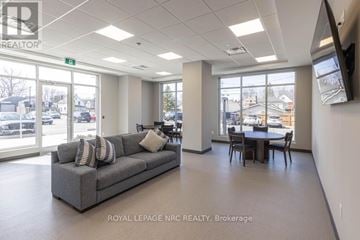 Port Colborne (Sugarloaf) condo for rent - A spacious living room with a grey sofa and a television mounted on the wall.