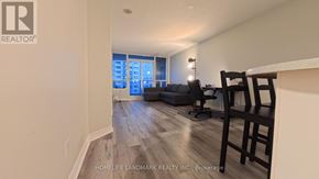 Toronto (Bayview Village) condo for rent - A realtor logo is on the wall of a room with a couch and chairs.