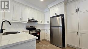 Markham townhouse for rent - A kitchen with white cabinets and a stainless steel refrigerator.
