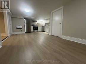Toronto (Mount Dennis) apartment for rent - A spacious kitchen with wood flooring and white walls.