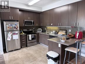 Waterloo townhouse for rent - A kitchen with a refrigerator, microwave, oven, and other appliances.