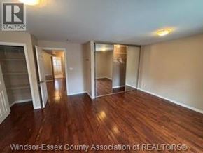 Windsor apartment for rent - A room with wooden floors and white walls, with a logo in the top left corner that reads "REALTOR".