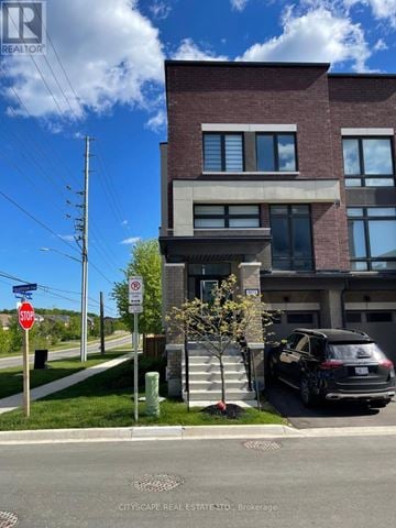 Oshawa (Samac) townhouse for rent - A modern brick building with a car parked in front.