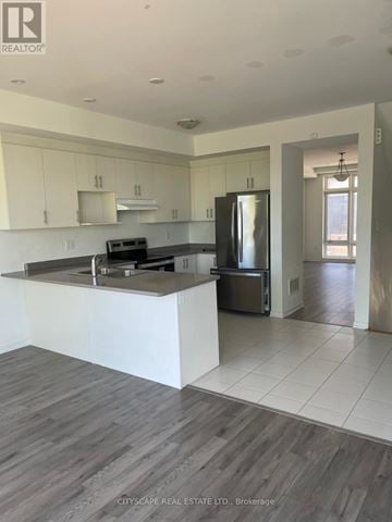 Oshawa (Samac) townhouse for rent - A modern kitchen with white cabinets and a wooden floor.