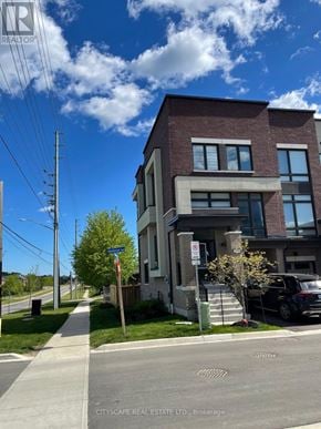 Oshawa (Samac) townhouse for rent - A modern brick building with a clear blue sky above it.